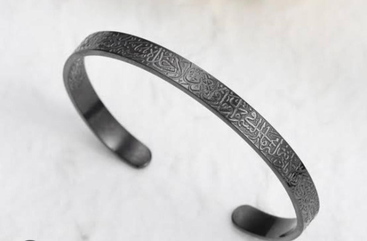 Matte black open cuff bracelet featuring intricate engraved Arabic calligraphy